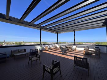 A wooden deck with chairs and a table under a roof.